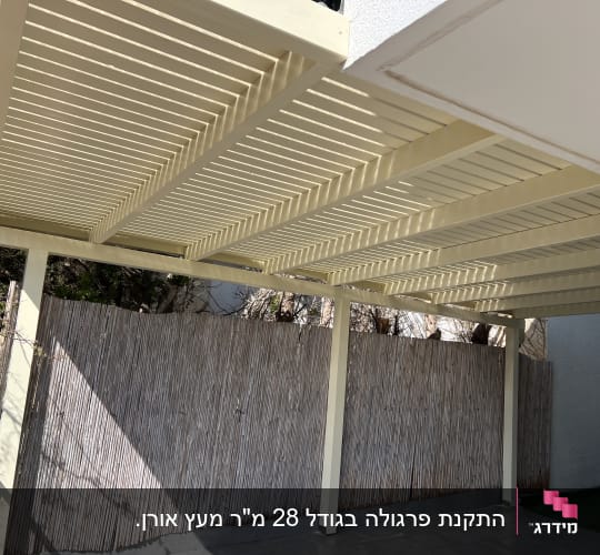 פרגולה מעץ עם גדר במבוק בחצר